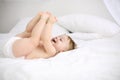 Happy little baby in nappy lies on white bed and Royalty Free Stock Photo