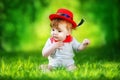 Happy little baby in red hat having fun in the park on solar glade. Summer vacations concept. The emotions. Royalty Free Stock Photo