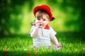 Happy little baby in red hat having fun in the park on solar glade. Summer vacations concept. The emotions. Royalty Free Stock Photo