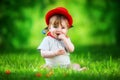 Happy little baby in red hat having fun in the park on solar glade. Summer vacations concept. The emotions. Royalty Free Stock Photo