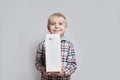Happy little blond boy is holding a big white carton package. Light background Royalty Free Stock Photo