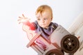 Happy little blond boy plays wizard and tries to revive a wooden cat. He sits on the floor against the background of a light