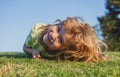 Happy little blond child laying on the grass in the park. Smmer day during school holidays. Amazed kid boy dreaming and Royalty Free Stock Photo