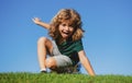 Happy little blond child laying on the grass in the park. Smmer day during school holidays. Amazed kid boy dreaming and Royalty Free Stock Photo