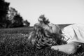 Happy little blond child laying on the grass in the park. Smmer day during school holidays. Amazed kid boy dreaming and Royalty Free Stock Photo