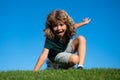 Happy little blond child laying on the grass in the park. Smmer day during school holidays. Amazed kid boy dreaming and Royalty Free Stock Photo