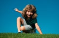 Happy little blond child laying on the grass in the park. Smmer day during school holidays. Amazed kid boy dreaming and Royalty Free Stock Photo