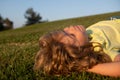 Happy little blond child laying on the grass in the park. Smmer day during school holidays. Kid boy dreaming and smiling Royalty Free Stock Photo