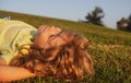 Happy little blond child laying on the grass in the park. Smmer day during school holidays. Kid boy dreaming and smiling Royalty Free Stock Photo