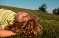 Happy little blond child laying on the grass in the park. Smmer day during school holidays. Kid boy dreaming and smiling Royalty Free Stock Photo