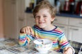 Happy little blond kid boy eating cereals for breakfast or lunch. Healthy eating for children. Royalty Free Stock Photo