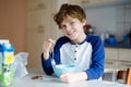Happy little blond kid boy eating cereals for breakfast or lunch. Healthy eating for children. Child in colorful pajama Royalty Free Stock Photo