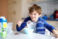 Happy little blond kid boy eating cereals for breakfast or lunch. Healthy eating for children. Child in colorful pajama Royalty Free Stock Photo