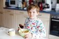 Happy little blond kid boy eating cereals for breakfast or lunch. Healthy eating for children in the morning. Child in Royalty Free Stock Photo