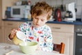 Happy little blond kid boy eating cereals for breakfast or lunch. Healthy eating for children in the morning. Child in Royalty Free Stock Photo