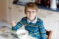 Happy little blond kid boy eating cereals for breakfast or lunch. Healthy eating for children. Royalty Free Stock Photo