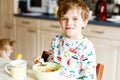 Happy little blond kid boy eating cereals for breakfast or lunch. Healthy eating for children in the morning. Child in Royalty Free Stock Photo