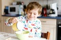 Happy little blond kid boy eating cereals and milk for breakfast or lunch. Royalty Free Stock Photo