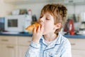 Happy little blond kid boy eating fresh croissant for breakfast or lunch. Healthy eating for children. Child in colorful Royalty Free Stock Photo