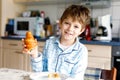 Happy little blond kid boy eating fresh croissant for breakfast or lunch. Healthy eating for children Royalty Free Stock Photo