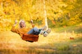 Happy little blonde caucasian girl smiling and riding a rope swing in autumn in the park Royalty Free Stock Photo