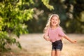 Happy little blonde girl listening to music with headphones, dancing and singing in nature in the Park. Royalty Free Stock Photo