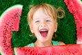 Happy little blonde girl lying on the grass with big slice watermelon in summer time Royalty Free Stock Photo