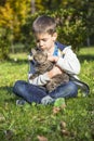 Happy little boy in the autumn park with pet kitten. Royalty Free Stock Photo