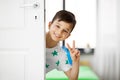 Happy little boy behind door at home showing peace