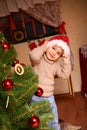 Happy little boy in a cap of Santa Claus standing near a Christmas tree Royalty Free Stock Photo