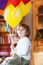 Happy little boy celebrating his 4 birthday with colorful balloons