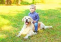 Happy little boy child and Golden Retriever dog is lying together on the grass on summer Royalty Free Stock Photo