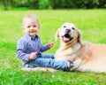 Happy little boy child and Golden Retriever dog is sitting together on the grass on summer Royalty Free Stock Photo