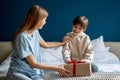 Happy little boy child opening wrapped gift box while celebrating his birthday with mother at home Royalty Free Stock Photo