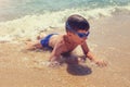 Happy little boy climbing on sea beach with waves Royalty Free Stock Photo