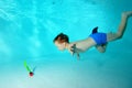 Happy little boy dives for a toy under the water in the pool and smiles. Royalty Free Stock Photo