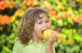 Happy little boy eating green apple. Smiling child holding and eats fresh apple, garden background. Portrait of cute Royalty Free Stock Photo