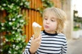 Happy little boy eating tasty ice cream cone outdoors during family stroll. Child have a snack on the go. Gelato is loved delicacy Royalty Free Stock Photo