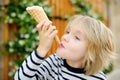 Happy little boy eating tasty ice cream cone outdoors during family stroll. Child have a snack on the go. Gelato is loved delicacy Royalty Free Stock Photo