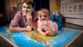 Happy little boy with father lying on big map and looking through magnifying glass. Concept of travel, tourism and child Royalty Free Stock Photo
