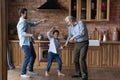 Happy little boy with father and mature grandfather dancing together