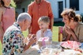 Happy little boy giving birthday present to his senior grandfather at generation family birthday party in summer garden Royalty Free Stock Photo