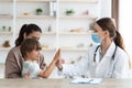 Happy little boy giving high five to professional woman doctor, sitting with mother at office, empty space Royalty Free Stock Photo