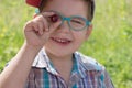 Happy little boy in glasses holds cherry at summer day outd