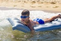 Happy little boy in goggles lying on air water mattress in sea Royalty Free Stock Photo