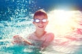 Happy little boy with goggles splashing in swimming pool Royalty Free Stock Photo