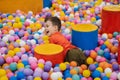 A happy little boy has fun jumping into a dry pool with colorful balls. The kid boy is playing and having a good time in Royalty Free Stock Photo