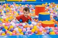 A happy little boy has fun jumping into a dry pool with colorful balls. The kid boy is playing and having a good time in Royalty Free Stock Photo