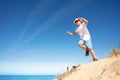 Cute boy in white jump from sand dune on a beach