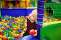 Happy little boy having fun in ball pit with colorful balls